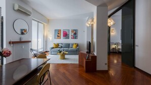 Een moderne woonkamer met een bank, salontafel en een eethoek met tafel en stoelen.