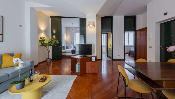 Een moderne woonkamer met een bank, salontafel, televisie en eethoek.