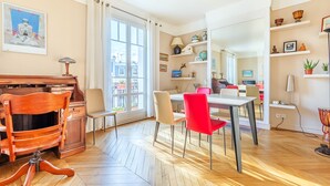 A dining area with a wooden piano, a table, and red and beige chairs. - Vue Exceptionnelle Sans vis à vis sur la Colline Montmartre, Calme et Spacieux (Paris)