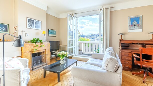 A living room with a fireplace, sofa, and a view of the city through large windows. - Vue Exceptionnelle Sans vis à vis sur la Colline Montmartre, Calme et Spacieux (Paris)