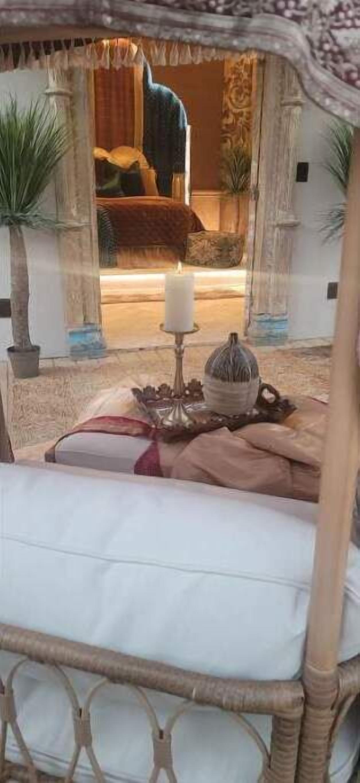 Un lit à baldaquin, une bougie et un bol décoratif sur la table de chevet.