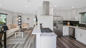 Una cocina moderna con armarios blancos, un refrigerador de acero inoxidable y una estufa a gas.