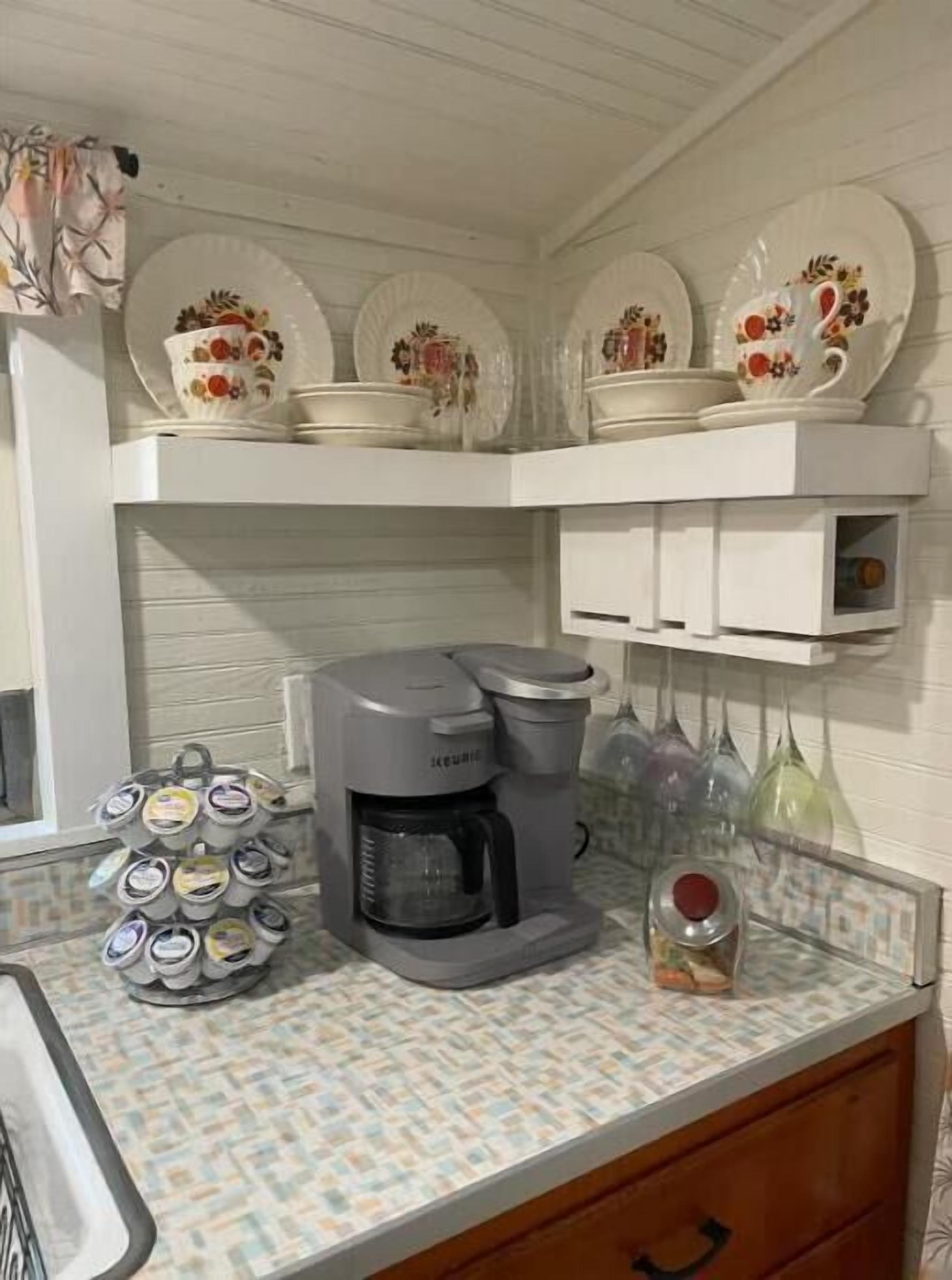 A kitchen with a coffee maker, a mug rack, and a dish rack.