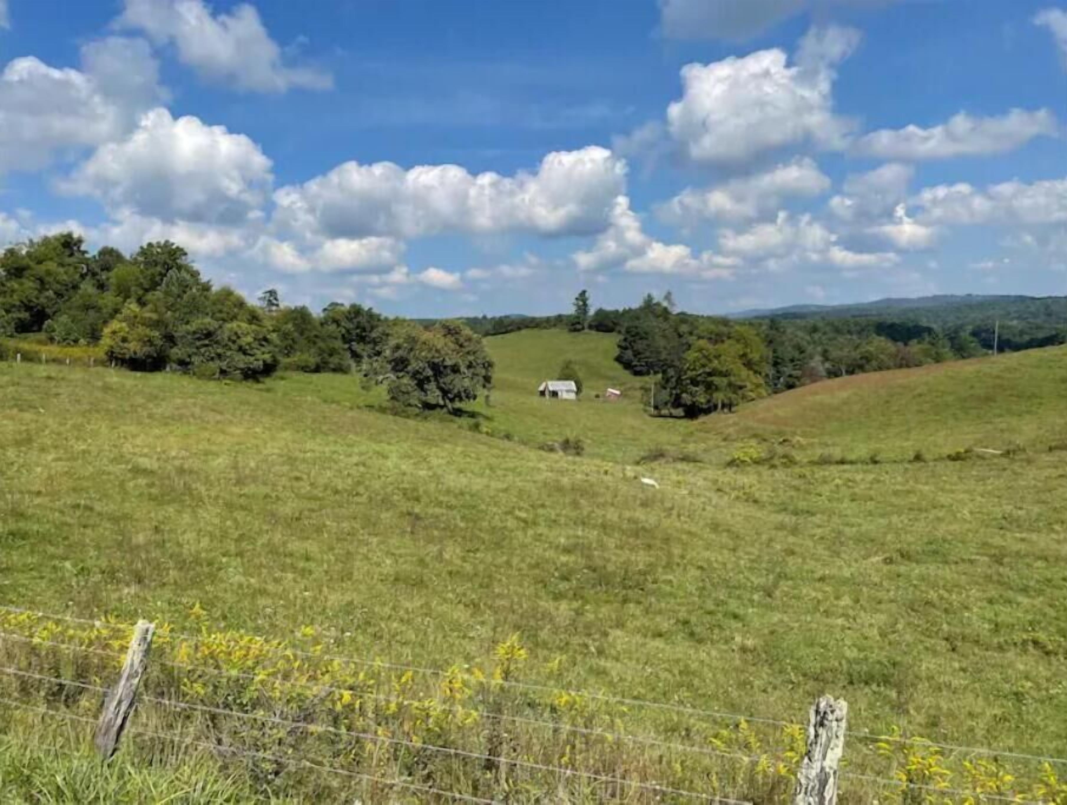 Un paisaje rural con una pequeña casa rodeada de vegetación y colinas.