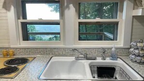 A kitchen with two windows, a sink, a stove, and a rack of kitchenware. - Breathtaking views amid a “PEACE” of heaven! (Fancy Gap)