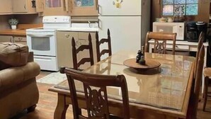 Una cucina accogliente con mobili in legno, un frigorifero bianco, un fornello e un tavolo da pranzo con sedie.