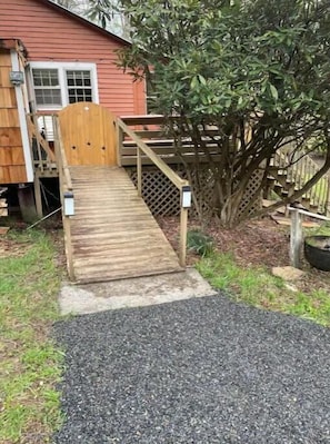 A wooden deck leading to a house with a red exterior.