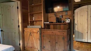 Una camera rustica in legno con un letto, un armadietto in legno con un cartello con scritto 'Gone Fishing', una televisione e un telefono.