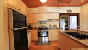 A kitchen with wooden cabinets, a stove, a refrigerator, and a sink. - Discover Melody Lodge, Ontario's Best-Kept Secret Where Tranquil Nature, Adventure, and Comfort Await. (Seeley's Bay)