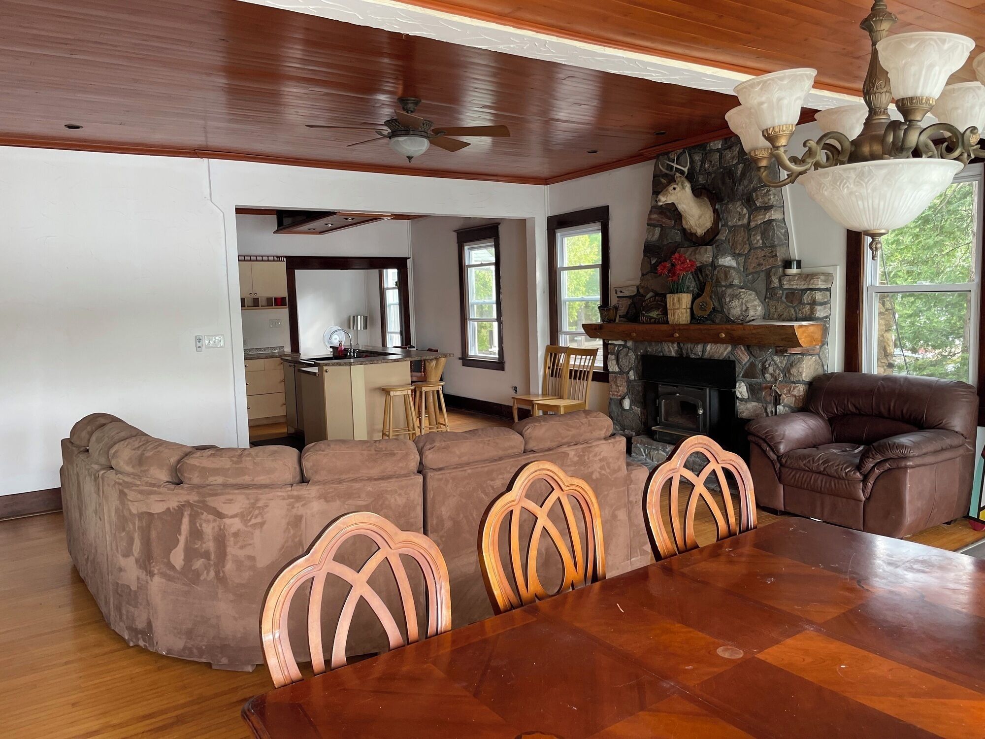 A spacious living room with a large wooden dining table, a stone fireplace, and a cozy seating area.