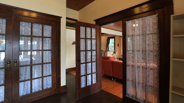 A hallway with wooden doors and a red sofa in the background. - Discover Melody Lodge, Ontario's Best-Kept Secret Where Tranquil Nature, Adventure, and Comfort Await. (Seeley's Bay)