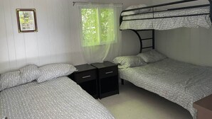 A dormitory room with two bunk beds, a small desk, and a window with sheer curtains. - Discover Melody Lodge, Ontario's Best-Kept Secret Where Tranquil Nature, Adventure, and Comfort Await. (Seeley's Bay)