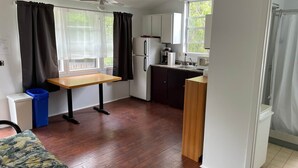 Eine kleine Küche mit einem Holztisch, einem Kühlschrank, einer Mikrowelle und einem Spülbecken.