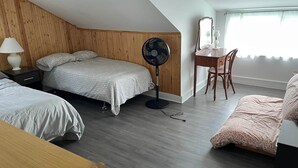 Ein Schlafzimmer mit einem Bett, einem Schreibtisch, einem Stuhl, einem Ventilator und einem Fenster.