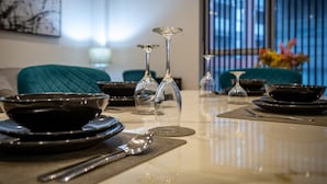 A dining table set with black bowls, spoons, and wine glasses, with teal chairs and a window in the background. - Large Apartment by Spinningfields - Manchester - Pass the Keys (Salford)