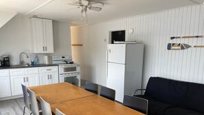 Una cocina moderna con armarios blancos, una mesa de comedor de madera y un sofá negro.