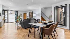 Ein modernes Wohnzimmer mit Essbereich, ausgestattet mit einer Couch, einem Tisch mit Stühlen und einer Treppe.
