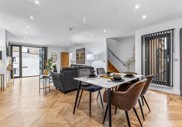 Un salon moderne avec un coin repas, comprenant un canapé, une table avec des chaises et un escalier.