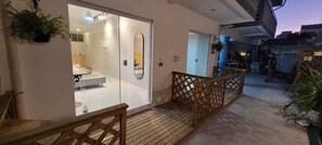 A modern bathroom with a glass shower enclosure, a wooden deck, and a staircase leading to an outdoor area. - POUSADA VALPARAISO (Florianópolis)