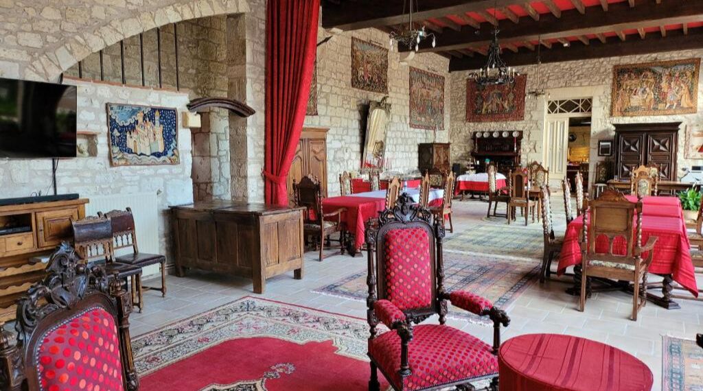 A spacious room with a stone wall, wooden furniture, and red drapery.