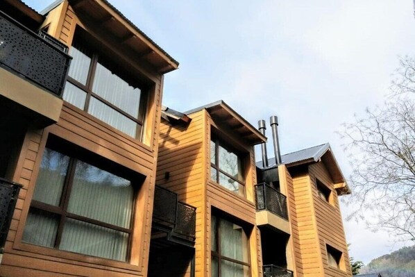 Un immeuble à plusieurs étages, doté d’une façade en bois et de grandes fenêtres.