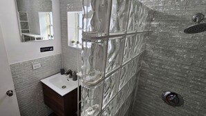 A bathroom with a glass shower enclosure, a sink, and a mirror. - Sirena Azul SoBe Suite 1 (Miami Beach)