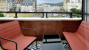 A balcony with two red chairs and a small table, overlooking a marina and buildings. - Appartement Cosy vue Port (Dives-sur-Mer)