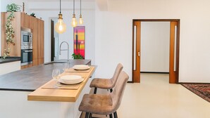Een moderne keuken met een centraal eiland, houten keukenkastjes en een eethoek met een bank en tafel.