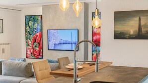 Een moderne keuken met een centraal eiland, een roestvrijstalen spoelbak en hanglampen.