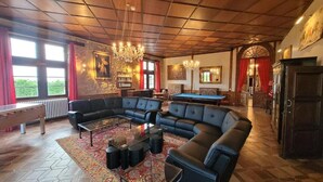 Amplia sala de estar con mesa de billar, sofás de cuero y zona de billares.