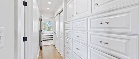 A hallway with white cabinetry and a wooden floor.