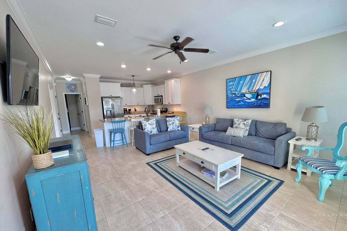 A modern living room with a sofa, coffee table, and a dining area with a kitchen in the background.