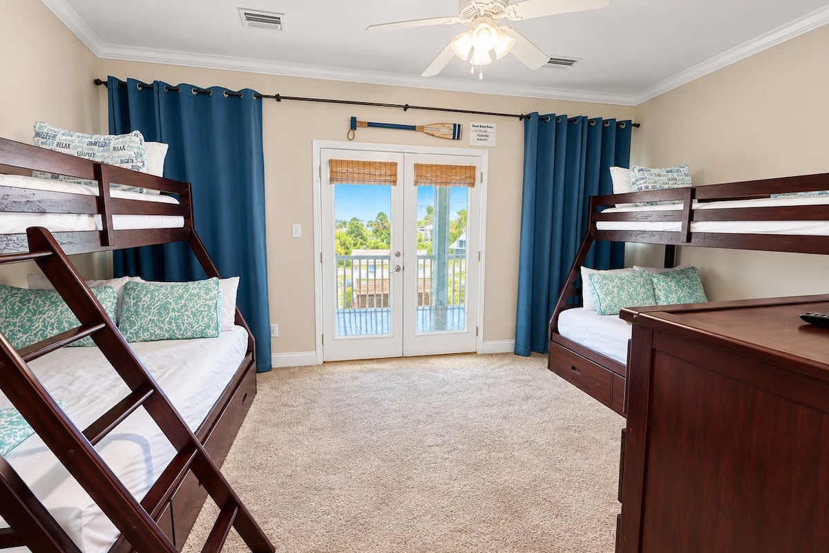 A room with bunk beds, a ceiling fan, and a view through a glass door.