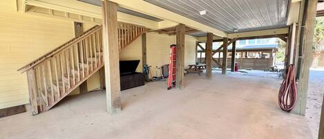 A covered outdoor area with a wooden staircase, concrete floor, and a red fire extinguisher.