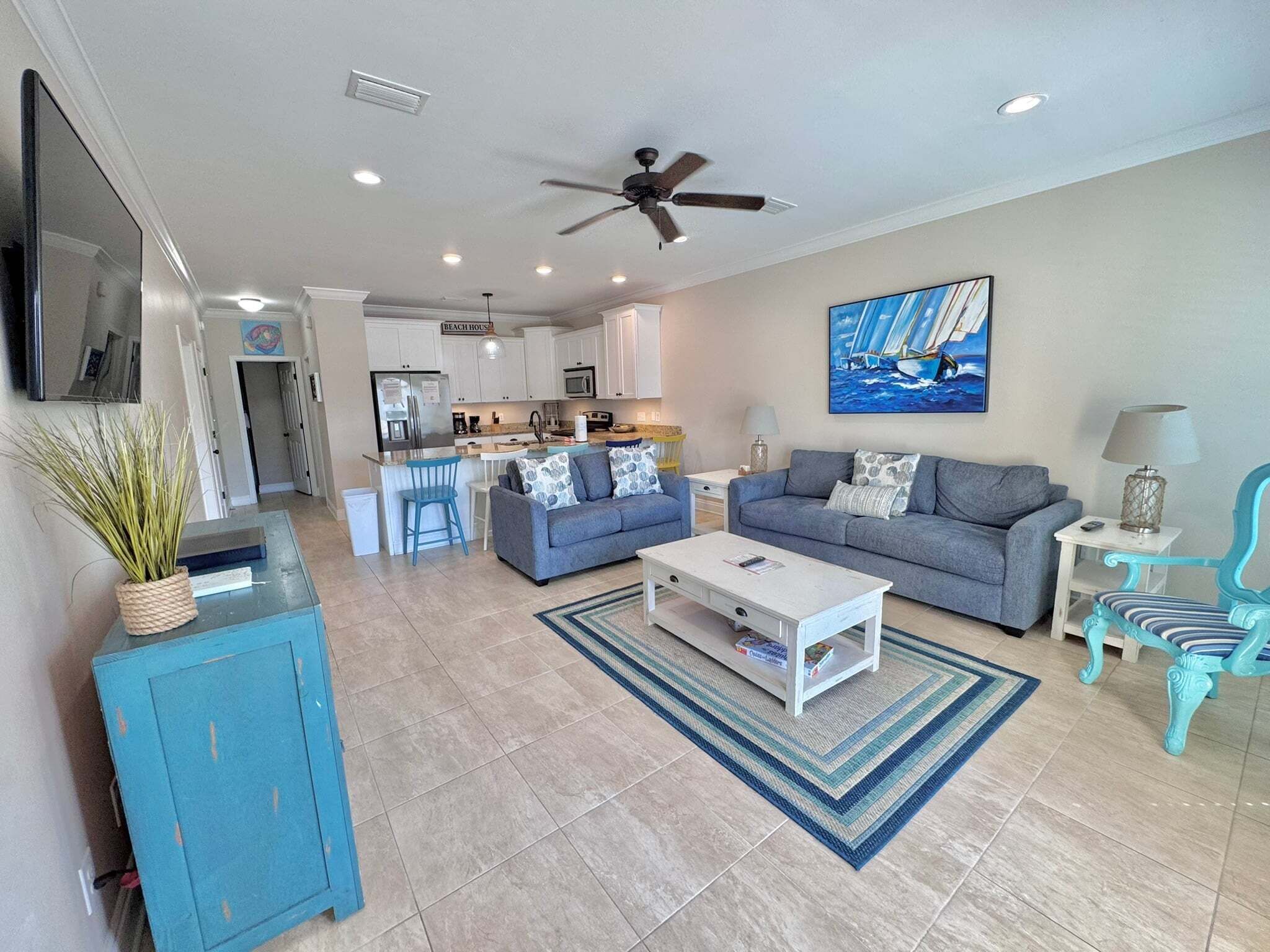 A modern living room with a sofa, coffee table, and a dining area with a kitchen in the background.