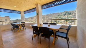 A terrace with a wooden ceiling, a table with chairs, and a view of a cityscape. - VillaMira GuestHouse 2 Downtown Amman (Amman)
