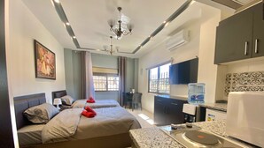A hotel room with two beds, a kitchenette, a dining area, and a large window. - VillaMira GuestHouse 2 Downtown Amman (Amman)