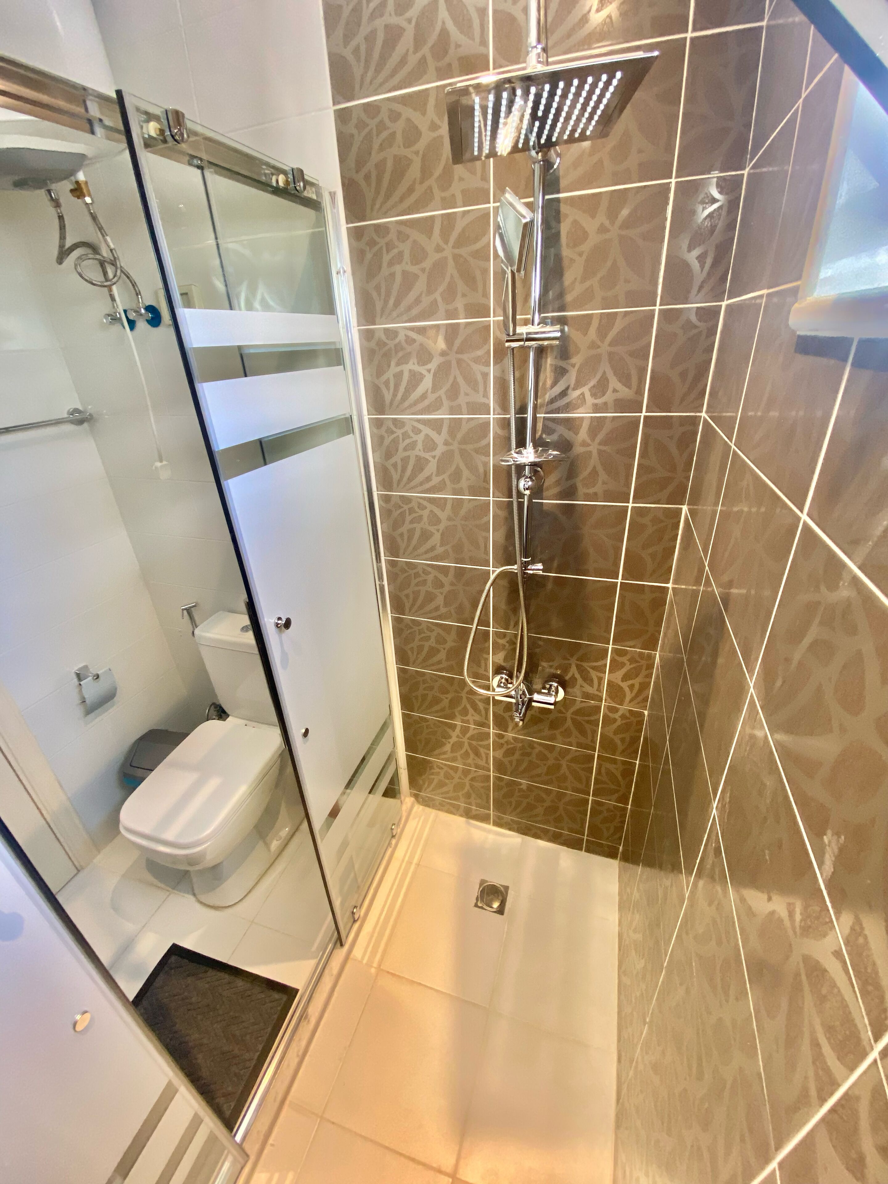 Een moderne badkamer met een douchecabine van glas, een toilet en een wastafel.
