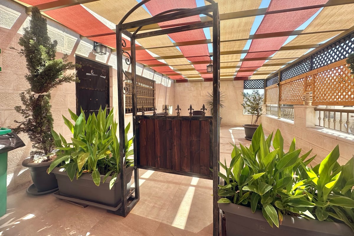 A courtyard with a wooden reception desk, potted plants, and a metal gate.