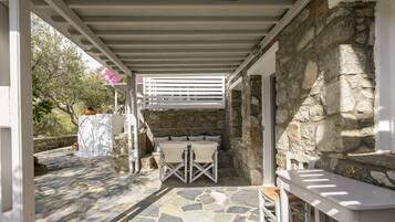 An outdoor patio with stone flooring, white furniture, and a stone wall.