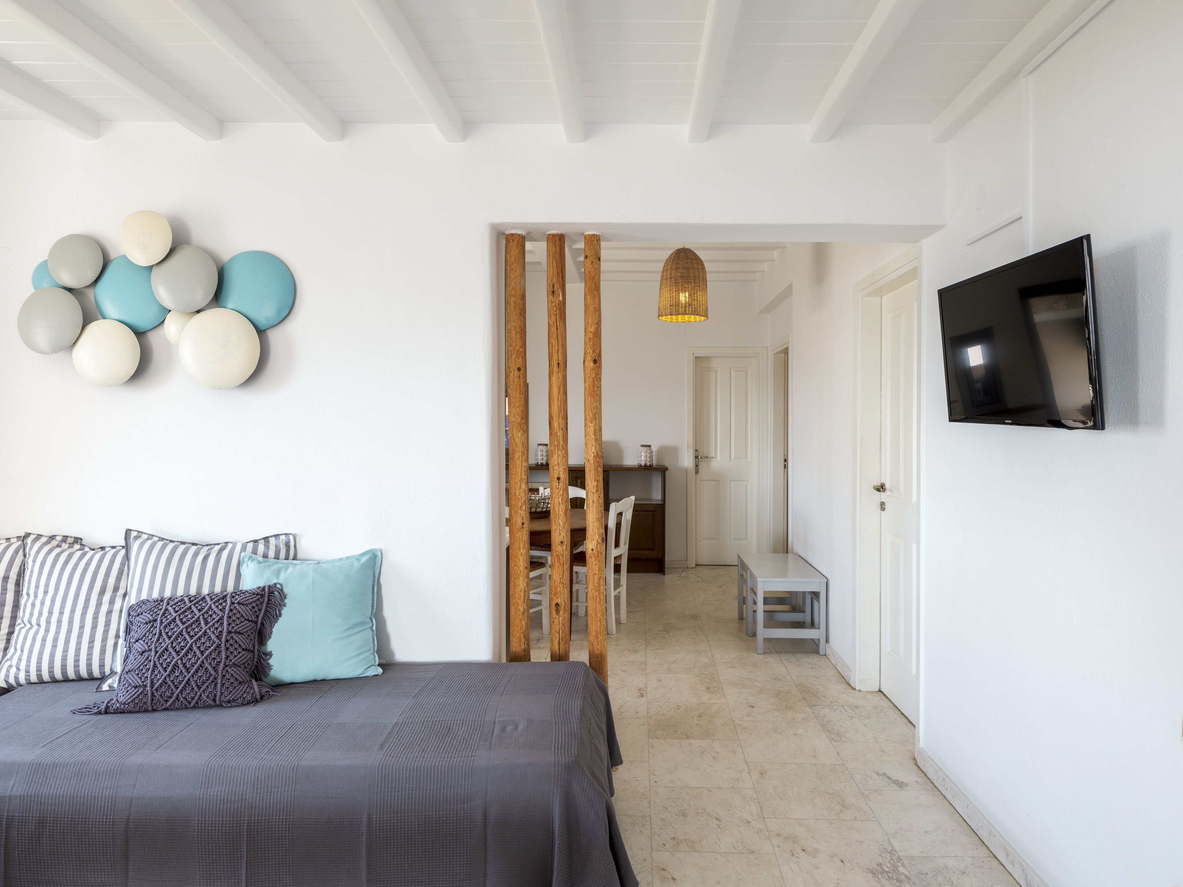 A bedroom with a bed, pillows, a wall-mounted TV, and a decorative wall piece.