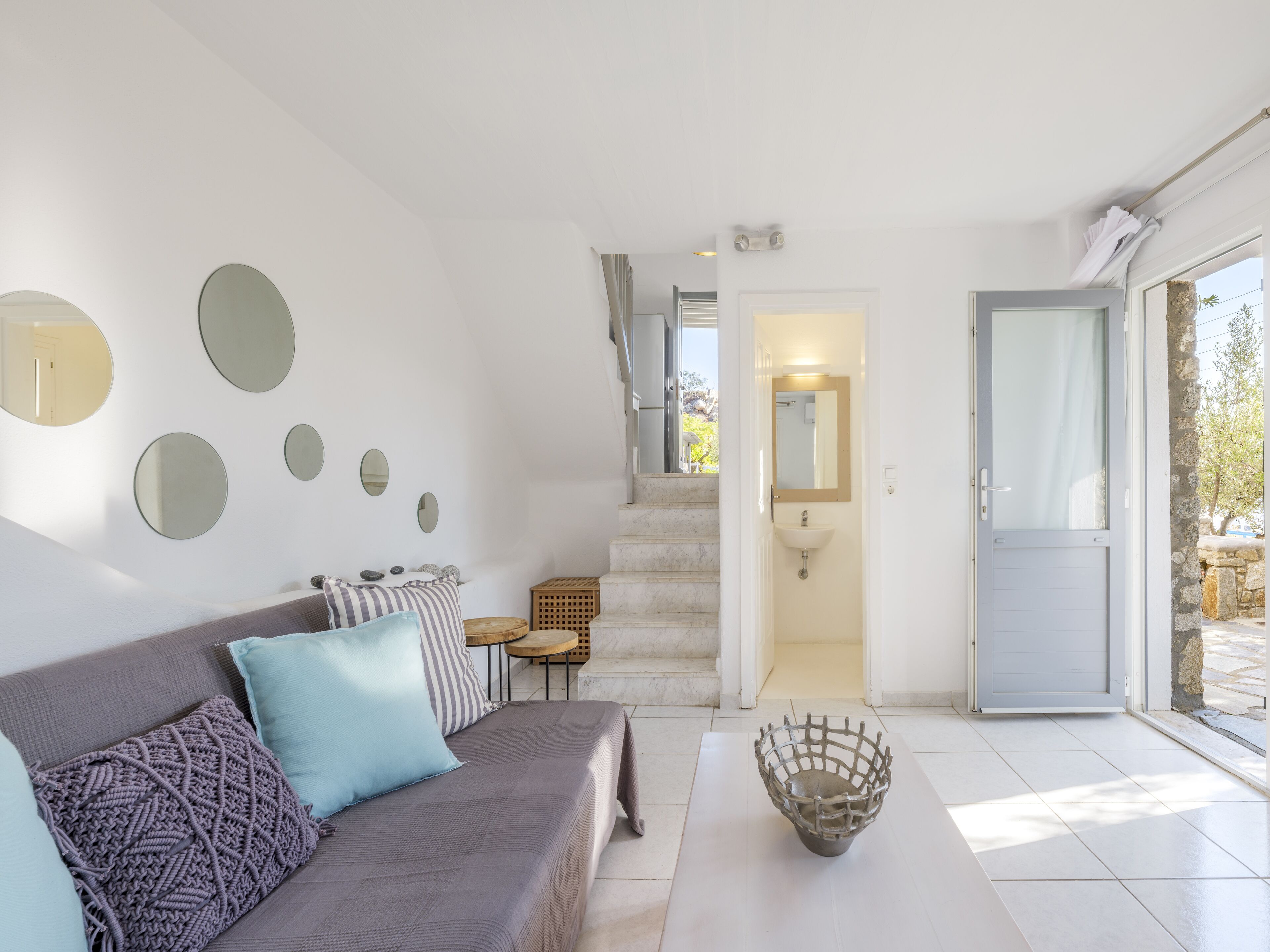 Een moderne woonkamer met een grijze bank, een salontafel en een trap naar een badkamer.
