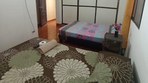 Un dormitorio con una cama, un televisor montado en la pared y un ventanal con cortinas.