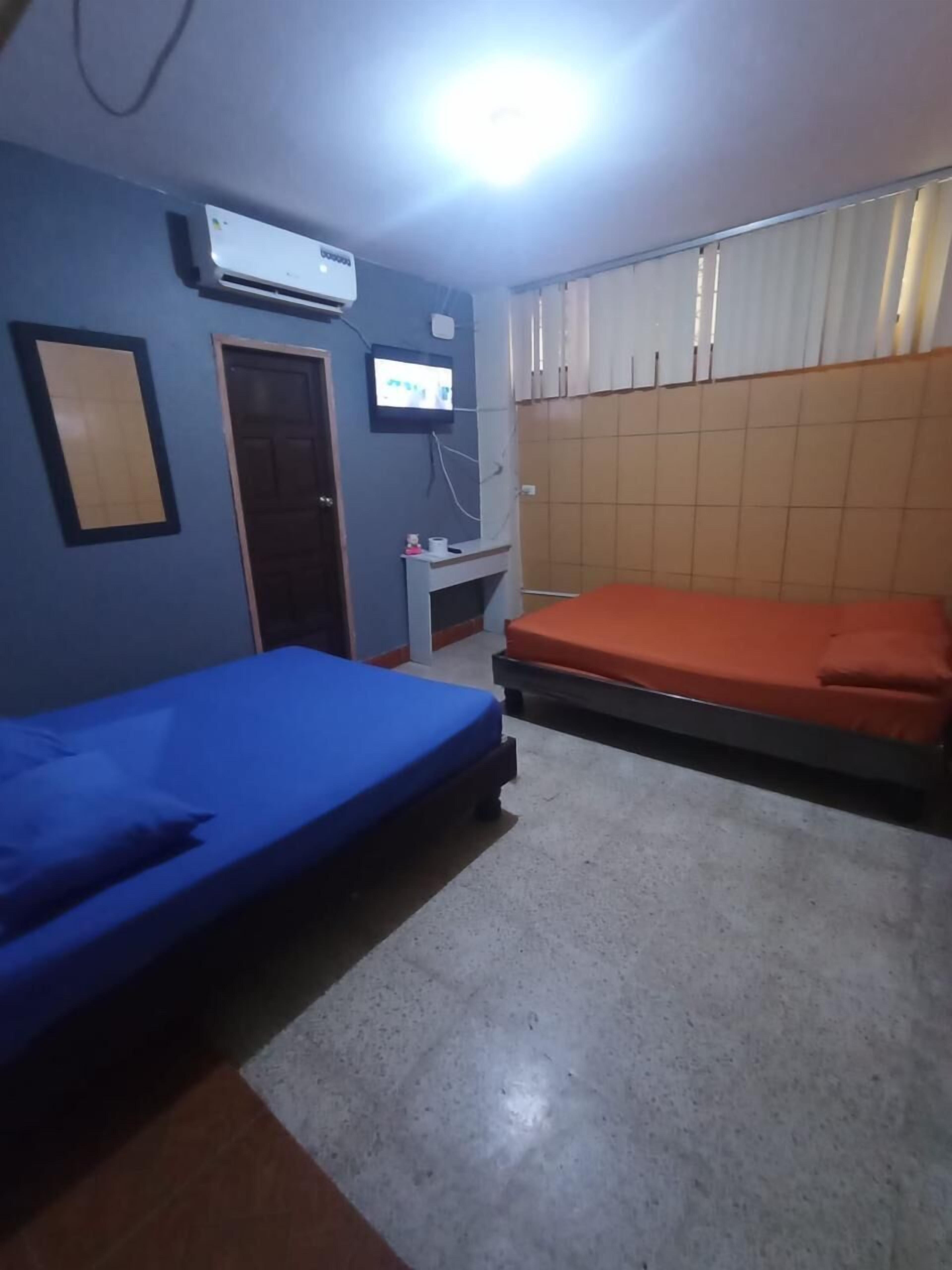 A room with two beds, a TV, and an air conditioner.