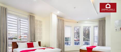 A hotel room with two beds, large windows, and a balcony.