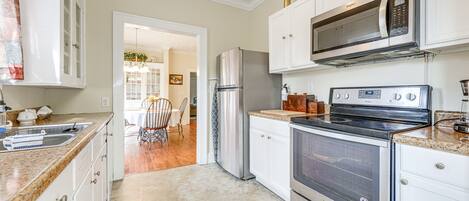 A kitchen with white cabinets, stainless steel appliances, and a granite countertop.