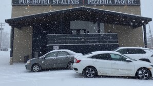 Ein Gebäude mit einem Schild, auf dem „PUB-HOTEL ST-ALEXIS PIZZERIA PAQUET“ steht.
