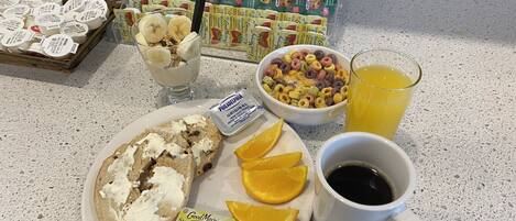 A breakfast table with cereal, milk, orange slices, coffee, and a glass of orange juice.