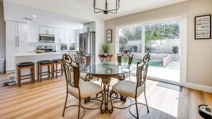 A modern kitchen with white cabinets, stainless steel appliances, and a glass dining table surrounded by chairs.
