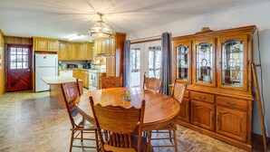 Una cocina amplia con armarios de madera, una mesa de comedor y un mueble grande de madera con puertas de cristal.